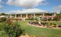 454 Rouse Street Tenterfield NSW PERFECTION - Peaceful Tree Change. $499,000.00 Close to the famous Tenterfield Golf Club, this exquisite quality built sandstone block home is set on 2.2 glorious acres surrounded by a beautiful and secret garden on the edge of town. This masterpiece has 87 square metres of verandah wrapped around the home taking full advantage of the elevated position with terrific views. The tastefully designed home features 4 spacious bedrooms with built ins; main with ensuite, a country style New Guinea Rosewood kitchen, dining and lounge room with central wood heating, plush bathrooms and large laundry. This classy home possesses a contemporary design with a flare of elegance featuring quality finishes including decorative plaster cornices, colonial architraves and windows, dado rails and solid brass hardware throughout. The well thought out garden features a beautiful fishpond with waterfall, bearing fruit trees, 120 roses and a huge variety of cool climate trees and shrubs. To help with the maintenance in the garden there is a licensed bore with electric submersible pump with an extensive drip irrigation system to the whole block. Double garage with remote door and internal access, and a large colorbond shed with power, phone, toilet facilities and ample workshop space. This property has plenty of room to conduct a home business.