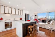 105/18 Bent Street Kensington VIC 3031 Luxury and Lifestyle with Spectacular City Views This stunning two bedroom apartment within “The Kensington” boutique complex, epitomises everything urban living represents, boasting an ideal city fringe location, generous open floor plan and contemporary, elegant design. Bathed in natural light, a central gourmet kitchen separates dining and lounge, spilling seamlessly onto a huge entertainer's balcony with spectacular, sweeping city views. Stone wrapped island/meals and bench tops, luxury stainless steel Smeg appliances, glass splashback, pull out pantry and soft close Hettich drawers feature in the crisp, white kitchen, whilst the lounge boasts a sleek, minimalist fireplace. Two large double bedrooms with generous built-in robes, deluxe master with spacious fully tiled ensuite including bath, and a large private balcony, also with city views, provide excellent accommodation. Safety and ambience have been incorporated with central video surveillance, intercom, secure building and underground carpark (with storage) entry and a landscaped, elevated garden in the enormous complex courtyard. Other impressive features include reserve cycle air conditioning, quality carpets, tiles and timber flooring. General Features Property Type: Apartment Bedrooms: 2 Bathrooms: 2 Outdoor Features Carport Spaces: 1
