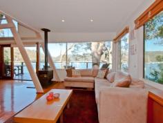 97 Richard Road Scotland Island | PMC Hill Real Estate Stylish and spacious this cedar waterfront home is filled with
natural light and enjoys the tranquil surrounds of Pittwater while
offering stunning views to Church Point and the Ku-ring-gai National
Park.
Flexible in its two storey design the home features polished timber
floors throughout and elevated 180 degree views to the National Park in
the west. The home is located close to the main ferry wharf which
provides easy access to Church Point which is only 3 minutes away.
The centrally located large modern kitchen incorporates a breakfast
bar and dishwasher and flows effortlessly to the open plan lounge/dining
room with a wide picture window and bifold doors which open to a full
width balcony. A generously sized bedroom or home office, a third
bedroom and a combined bathroom/laundry are also on this level.
The spacious master bedroom is located on the upper level with
built-ins and sparkling water views through spotted gums. A full sized
second bathroom and a cute A shaped child's bedroom with a loft cubby
complete the upper level.
At the rear a large timber deck is ideal for entertaining and the
grassed garden is perfect for children to play. The home has plenty of
under house storage which, subject to approval, could be converted into
more rooms if required.
Timber stairs and pathways lead through the fully landscaped front
garden to the waterfront facilities which consist of a deep water jetty
with a large entertaining landing and pontoon.
This home will impress families seeking space, comfort and lifestyle.