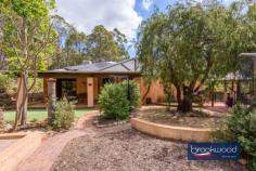 3165 Victoria Rd Hovea WA 6071 $949,000 Live connected to nature on this spectacular Hovea property located on the border of John Forrest National Park. Minutes from Hovea Falls and kilometres of walking and riding trails, the 3 bedroom 2 bathroom home sits in a natural landscape with a canopy-level balcony that makes it feel like a treehouse. Fruit trees, vegetable gardens, rainwater tanks, solar panels and a storage battery lighten your footprint while the availability of scheme services provides security. This mesmerising environment is an idyllic habitat for humans and creatures, and the appearance of resident kangaroos, Red Tail Black cockatoos, Boobook Owls, Quendas and Echidnas is a thrilling reminder of the richness and rare beauty of nature. 3 bedrooms 2 bathrooms 1984 built brick and iron Multiple living zones Indoor-outdoor floorplan N-facing tree-top balcony Pwd workshop auto retic 6 kW solar 9.7 kW battery Decked above-ground pool 2 ha block paved driveway Spectacular natural oasis Moving through the landscape to arrive at this Hovea home feels like ascending to another realm, a secret world where native flora and fauna and the rhythms of nature direct and enrich each day. Cocooned by a degree of self-sufficiency and with endless opportunities to play, explore and discover the natural environment; this property delivers the shelter of a warm and inviting home and the nourishment and inspiration of a stunning and unique Hills location. The home displays a modern organic vibe with predominately neutral material and colour palettes interrupted by bursts of rich, warm colours and the use of robust natural materials. A central open plan bathed in light from a skylight, flows seamlessly to a formal entertaining space – currently used as a music room – and a north-facing sunroom with full-height glazing. The sunroom opens onto the verandah spanning the front of the home to create an all-season, indoor-outdoor living space that appears to float in the treetops and views to the decked gazebo and sparkling swimming pool. An intrinsic connection to nature is seen across the home, in the granite feature wall behind the slow combustion fire, the tactile, organic form of wooden handles on the kitchen cabinets, and the smooth, textured surface and subtle colour shifts of slate floors. In the beating heart of this home lies an updated modern kitchen, replete with stone benchtops, a suite of stainless-steel appliances and abundant storage. The master suite is positioned discreetly at the front of the home with polished concrete flooring and sliding door access to a wide verandah. Complete with a walk-in robe and semi-ensuite connecting through to the living hub. The junior wing housing two large bedrooms, a light filled family bathroom and walk-through laundry is tucked to the rear of the home. A commitment to stepping lightly is evident across the property. Reticulated vegetable gardens, wicking beds, fruit trees, and a chicken run bring self-sufficiency. Scheme water is available, and power is connected. Still, rainwater tanks, solar panels and a storage battery reduce dependence on the grid, and a large, powered workshop with 3 open bays provides a practical space for at-home projects and repairs. With 4.94 acres to explore and John Forrest National Park, The Heritage Trail, Eagle’s View walk and Hovea Falls at the bottom of the driveway, days of adventure and wonder await. Bike and walking trails in the national park have been extended and subjected to considerable upgrades in recent months, with further improvements planned. More sedate pastimes can be found at the much-loved Parkerville Tavern, an easy, level walk away along the Heritage Trail. It is rare to find a property of this character, a home that meets the ideal of Hills living so completely with the space and freedom of a 4.94-acre lot, adjacent to a national park, within easy reach of schools and Mundaring Village yet shrouded in the blissful beauty of nature and a sense of isolation.
