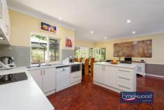 11 Hawkstone Street Gidgegannup WA 6083 $1,200,000 A gently graded landscape rolls from the road to a hidden glen and quality-built family home surrounded by ample outdoor living and entertaining space. The home boasts a flowing floorplan, formal and informal living and dining high ceilings and a bright neutral palette. 4 bedrooms 2 bathrooms 1990-built brick and iron High ceilings throughout Open plan & formal living Multi outdoor entertaining Principal suite private patio Separate jnr bedroom wing Powered studio & workshop 5-acres with high-yield bore Hideaway with convenience A wide stone staircase leads to the home’s front door and formal entry, but the south-facing door into the open-plan living zone most often welcomes friends and family. This casual, friendly welcome sets the tone for a relaxed, family-focused lifestyle. Approached via a wide stone staircase, the home’s formal entry has a sense of grandeur and sophistication. Yet, the backdoor – opening from a south-facing patio embodies the true spirit of this welcoming residence. Step inside via this ‘friends’ entrance, and the luminous style of the open-plan kitchen, meals, and family room immediately embraces you. Parquet floors run underfoot, and large windows to the north and south fill the room with natural light and garden views. A slow-combustion fireplace casts a cosy glow, and split-system air conditioning ensures year-round comfort. High ceilings emphasise the volume and ease of the flowing floorplan, setting the stage for a relaxed, family-oriented lifestyle. A thoughtfully designed kitchen beckons with its stone-topped island and breakfast bar– ideal for morning coffee or casual meals. Surrounding the electric oven and cooktop, an L-shaped benchtop provides ample workspace, while a dishwasher, extensive cabinetry, and a large walk-in pantry keep the space pristine and organised. The formal living and dining rooms extend from the main entry. Here, polished parquet floors gleam in the light of an open fireplace, creating an atmosphere of warmth and refinement. Adjoining the lounge, the formal dining room connects to the south-facing patio, perfect for alfresco dining or evenings spent entertaining. From the open-plan hub, a private junior wing offers a quiet retreat. Three well-appointed bedrooms – two with carpets and built-in robes, one with parquet flooring – provide a flexible backdrop for the tastes and needs of kids of all ages. Featuring a claw-foot bathtub, the family bathroom has a measure of old-fashioned charm. A walk-through laundry with abundant storage and a separate WC complete the layout in the junior wing. Picture yourself waking up in a serene primary suite, where French doors open to a verandah draped with wisteria. This is your private haven, complete with plush carpeting, a split-system air conditioning unit, and a spacious walk-through robe leading to an ensuite featuring a double vanity, a shower, and a WC. Set on a 5-acre lot, this home is a sanctuary of privacy and possibility. Imagine strolling through arbours, enjoying the changing seasons in the gardens, or retreating to the powered brick studio for creative pursuits. A powered workshop provides ample space for projects or hobbies. The property is as functional as it is beautiful, with a productive bore and filtration system supplementing generous rainwater tanks, a choice of nearby schools including Mundaring Christian College, Parkerville Primary School, Parkerville Steiner School and Silver Tree Steiner School along with school pickup on Roland Road. The nearby Parkerville Tavern is a family-friendly local, and the Gidgegannup township boasts a much-loved bakery, local doctors, a chemist, and fuel. Midland and Mundaring, with their extensive services and amenities, are both an easy drive away. Whether you’re seeking space for work, play, or to unwind, this property delivers on every level. Designed for modern living with a home filled with peace and tranquillity. Welcome home.