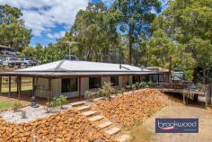 23 Duncan Pl Mahogany Creek WA 6072 $899,000 This utterly charming Hills-style property combines an open-plan layout with a contemporary colour scheme and styling. It sits on a landscaped lot at the end of a cul-de-sac, with a large north-facing deck sheltered by a majestic central eucalypt. Ideally suited to young couples, families, or those seeking a lifestyle that balances a connection to nature with access to amenities, this home is designed for modern life. It is just minutes from Mundaring Village and close to numerous schools, parks, and bushland trails. 4 bedrooms 2 bathrooms 1987-build Hardi and iron Wrap-around verandah North-facing deck gazebo Landscaped grounds retic 8 X 8 powered workshop Paved off-street parking Evap RC AC SC fireplace 1995 sqm cul-de-sac lot Modern Hills classic Behind a wide wooden door that hints at the character within, this thoughtfully reimagined 1984-built home strikes a perfect balance between contemporary comfort and Hills’ authenticity. A sensitive renewal has imbued the home with a relaxed sensibility, where every element feels considered. Timber-lined ceilings and recycled brick lend warmth and texture, while a soft, muted palette enhances the natural light. The informed use of materials — both timeless and practical — creates a home that is as stylish as it is liveable, effortlessly blending modern design with the realities of everyday life. The result is a sanctuary that feels at once considered, welcoming, and unmistakably of its place. A slow-combustion fireplace with a recycled brick surround offers both warmth and a grounding presence in the open-plan living zone. The well-appointed kitchen enhances this sense of calm and welcome. Cabinetry in a soft blue-grey tone wraps around a 900mm stove and integrated dishwasher, creating a refined yet practical workspace. A white farmhouse sink and herringbone-tiled splashback complete the modern farmhouse aesthetic, striking a balance between functionality and style — equally suited to everyday meal prep or lively gatherings with family and friends. A ranch-style floor plan ensures ample light and views of the surrounding landscape from each bedroom. The principal suite — large enough to accommodate a king-sized bed — boasts a walk-in wardrobe and ensuite and is fitted with a reverse-cycle air conditioner. Perched in an elevated position, the deck extending from the verandah captures the essence of relaxed, open-air living. Dappled light filters through the canopy above, creating an ever-changing play of shadow and sun. This idyllic outdoor space is designed with gatherings in mind and is generously proportioned to accommodate a large dining table and BBQ. Imagine the soft rustle of leaves overhead, the glow of festoon lights strung above, and the laughter of friends and family echoing into the evening — a setting where unforgettable moments are effortlessly made. Terraced retaining walls are topped with architectural plantings that add structure and greenery to separate the home from the workshop. Framed by lawn edges and bathed in northern light, garden beds offer an ideal site to grow vegetables or train a series of espaliered fruit trees. The powered workshop sits at the top of the lot and has a concrete floor and double sliding doors. A paved hardstand offers room to park cars, a caravan, a boat, or a trailer. A path leads past a firepit and down a set of recycled brick steps to a rustic brick gazebo, which looks across a level lawn. The driveway continues along one side of the property, allowing drive-through access to the bottom of the lot. Set at the end of a peaceful cul-de-sac, this thoughtfully reimagined Hills home offers a harmonious blend of contemporary comfort and natural charm. Warm timber-lined ceilings, recycled brickwork, and soft, muted tones create a serene interior. Outdoors, a north-facing deck shaded by a central eucalypt, invites entertaining, while landscaped gardens and a versatile workshop add further appeal. Moments from Mundaring Village, schools, and bushland trails, this home promises an effortless lifestyle connected to nature.