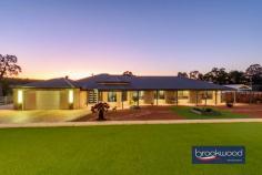 3 Owl Ln Gidgegannup WA 6083 $2,000,000 Perched atop a gentle rise on two hectares, this distinguished residence effortlessly fuses contemporary comfort and country living. The property boasts exceptional amenities and commands serene views across the undulating landscape to a tree-lined dam in the lower corner, creating a picturesque backdrop for daily life. 4 bedrooms 3 bathrooms 2012-built brick and iron Large lock up 2 car garage Extensive bitumen parking area Library office media room Poolside Cabana under main roof Large Alfresco & Entertaining Deck Below ground Solar heated pool 5.2Kw Solar system with 18 panels Plumbed powered man cave/granny flat 10 x 20 3 Phase Powered workshop w 2x hoists Heated spray booth with filtered extraction fan Bore, retic, 3-ph generator 2 hectares, 2 gated entrances Close to Mundaring & Midland shopping precincts Double doors reveal a sophisticated entry hall, where premium porcelain tiles extend across the thoughtfully conceived floor plan. The immediate impression is of space and light; the home’s exemplary attention to detail is evident from the first step inside to be welcomed by the multi-room music system throughout the home. To one side of the entry, a sophisticated media room demonstrates the home’s commitment to modern living. Fully wired for sound and featuring a statement bay window, this versatile space, with its plush carpeting, serves equally well for casual movie nights or more formal gatherings. An expansive open-plan living zone at the heart of the home creates a natural gathering point for family life. The contemporary kitchen is a study in modern elegance, with striking black Essa stone benchtops contrasting beautifully with slim black hardware on the abundant under-bench storage. A 900mm oven and induction cooktop cater to the serious cook, while the white two-door dishwasher maintains the kitchen’s crisp aesthetic. A dedicated coffee bar and walk-in pantry ensure the main workspace remains uncluttered and primed for culinary creativity. The central meals area flows naturally to a spacious family room, where direct access to the large Alfresco area leading to the sheltered below-ground salt pool that creates a seamless connection between indoor and outdoor living. This thoughtful layout epitomises modern Australian living, where every element has been carefully considered to deliver an easy, elegant lifestyle. The thoughtfully arranged accommodation wing extends from the family room via a central hallway. A delightful library with bespoke storage solutions creates a sophisticated retreat with the added luxury of direct pool access. Adjacent, a dedicated home office provides a focused environment for work or study, embodying the home’s commitment to balancing family life with professional needs. The main bedroom suite exemplifies sophisticated living, with sliding doors seamlessly connecting to the pool area. This generous parents’ retreat encompasses a king-sized bedroom finished with quality carpeting, sheers & blockout curtains, a walk-in wardrobe, and a refined ensuite, where fluted glass shower screens, double basins and a separate WC add elements of luxury and privacy. Junior bedrooms demonstrate equal attention to detail, each appointed with mirror-fronted built-in robes and a combination of Roman and Venetian blinds. These rooms are serviced by a bright family bathroom featuring a shower and tub, complemented by a practical arrangement where the separate WC is positioned within the walk-through laundry at the hall’s end. The outdoor living spaces have been curated to create a resort-style environment for year-round enjoyment. The centrepiece is a solar-heated salt pool protected by a shade sails and surrounded by sophisticated entertaining zones. These include a deck with an integrated teppanyaki bar and an air-conditioned cabana with bathroom facilities. Outdoor roll up awnings provide additional climate control, ensuring comfortable use of these spaces regardless of weather conditions. This thoughtful integration of indoor and outdoor spaces, combined with practical amenities and luxurious touches, creates a home where every aspect of modern family life has been carefully considered and catered for. Exemplary residential amenities set a high standard, and the workshop complex and grounds maintain this commitment to excellence, with an array of features elevating this estate beyond the ordinary. The crowning achievement is a magnificent 20m x 10m workshop, designed with 6.5m clearance and comprehensive 3-phase power. Two vehicle hoists and a dedicated spray booth create a premium workspace. This exceptional facility offers limitless potential for both passionate enthusiasts and professionals. A sophisticated ‘man cave’ has been created within the workshop complex which could be easily converted to a granny flat. This retreat has climate control, a complete kitchen, and bathroom facilities. A separate entry opens to a wrap-around verandah, perfect for relaxing after a day of projects. The auxiliary structures continue with a single carport and a powered 6m x 9m garage, complemented by two 40-foot sea containers thoughtfully converted and powered for machinery storage. Together, these create a comprehensive compound for vehicles and equipment. The 2-hectare grounds showcase intelligent planning. Extensive paving surrounds the home, and two substantial rainwater tanks (250,000 and 24,000 litres), a high-yield bore, and a winter dam ensure water security. Carefully placed outbuildings and statuary enhance the landscape, creating visual interest throughout the property. Every aspect of security and convenience has been considered: dual entry points with electric gates, comprehensive reticulation systems, a rooftop fire suppression system, monitored security alarm, CCTV and Intercom systems. 3 phase generator backup and extensive landscape lighting all contribute to a secure, low-maintenance environment. Solar powered hot water system and 5.2kw with 18 solar panels. Zoned reverse cycle air conditioning throughout the primary residence provides the final touch to what is truly a turn-key property. This remarkable Hills residence presents a rare opportunity to acquire a premium lifestyle property where every detail has been meticulously planned and executed, creating an environment where luxury and practicality coexist perfectly.