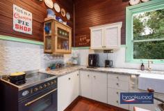 2965 Jacoby St Mundaring WA 6073 $1,000,000 In the heart of Mundaring, where the rhythm of modern life meets Western Australia’s pioneering past, stands a weatherboard and iron cottage that embodies the very essence of heritage living. Built circa 1901 by retired Bunbury harbour master Captain Thomas Scott, the remarkable “Stratheden” carries within its weatherboard walls the pioneering spirit that shaped early Western Australia. Hidden from the street by a charming picket fence and enveloped in lush, established gardens, this remarkable workers’ cottage offers a rare opportunity to inhabit a piece of living history whilst enjoying the unparalleled convenience of one of the region’s most coveted locations. 3 bedrooms 1 bathroom 1901 weatherboard & iron Striking workers’ cottage Extensive Jarrah panelling Wide jarrah floorboards High pressed metal ceilings Rear lane access to garage Estab gardens, bore retic 2023 sqm heart Mundaring Steps to Trail, park, village The extensive use of jarrah throughout this property immediately distinguishes it as a superior example of vernacular architecture, where wide floorboards and striking panelling speak to the craftsmanship and material abundance of a bygone era. Here, the integrity of the original fabric has been meticulously preserved, creating an authentic connection to the past that is increasingly rare. This is not simply a house that has been renovated; it is a heritage treasure that has been lovingly maintained, telling the story of Western Australia’s timber heritage. The approach to the home sets the tone for what lies beyond – a wide, bullnose verandah extends a gracious welcome, while pressed glass in subtle pastel hues surrounds the front door like jewels set within a frame. Living here means beginning each day with this gentle beauty, where morning light filters through coloured glass and the established gardens create a private sanctuary mere steps from Mundaring’s vibrant village centre. Upon crossing the threshold, the significance and integrity of this property become immediately apparent through the soaring ceiling, its pressed metal painted white, creating a striking vertical dimension that speaks to the generous proportions seen throughout the home. Picture rails and wide jarrah floorboards create a striking welcome that sets expectations high, and the home delivers on every promise. The entrance hall is flanked by two generously proportioned bedrooms, each graced with original windows, pressed metal ceilings and decorative fireplaces. At the end of the hallway, a pair of interior doors open to reveal the property’s masterpiece – a living room that embodies an authentic and uniquely Western Australian aesthetic. Vertical jarrah boarding rises to dado height, and horizontal panelling continues to the jarrah-clad ceiling. An expanse of eight-paned windows draws northern light into the heart of the home, creating a space where the seasons become part of daily life, where winter afternoons glow golden against the jewel-toned timber and summer mornings arrive soft and bright. Living in this room means inhabiting a space where craftsmanship and comfort converge, where every surface speaks to the skill of builders who understood both beauty and function. At one corner of this magnificent living space, a breakfast nook provides an intimate setting for morning rituals, whilst the kitchen represents a faultless melding of history and modern convenience. The original chimney breast and hearth, fitted with a Metters stove, anchor the space with authentic period detail, while pressed metal and jarrah panelling blend seamlessly with gold-flecked stone benchtops, under-bench cabinets, and contemporary appliances, including a freestanding electric oven and dishwasher. This kitchen exemplifies how heritage properties can incorporate modern elements without compromising their character. The principal bedroom, accessed via the living room, offers generous proportions. High ceilings ensure an airy, relaxed atmosphere that transforms sleep into restoration, whilst a separate walk-in robe and dressing room provide practical luxury. Reverse cycle air conditioning delivers year-round comfort, demonstrating that while heritage is honoured, contemporary expectations for comfort are uncompromised. Spanning the rear of the plan, a sunroom with a swathe of windows looking out to the rear garden creates a seamless connection between indoor and outdoor living. Terracotta floor tiles ground the space in earthy authenticity, while reverse-cycle air conditioning and direct access to both the rear garden and an alfresco entertaining zone ensure this bright space suits year-round use. A family bathroom and well-appointed laundry at either end of the sunroom complete the thoughtful arrangement of spaces. The transition to outdoor living occurs through French doors that connect the sunroom to a large, crazy-paved patio set beneath a wisteria-threaded pergola – a space where entertaining becomes effortless and where the changing seasons provide an ever-evolving backdrop. Living here means experiencing the joy of alfresco dining where privacy and tranquillity coexist with incredible accessibility to village amenities. The current owner’s dedication as a skilled and passionate gardener has created botanical magic that transforms this property from merely impressive to utterly enchanting. Bore reticulated lawns and gardens cocoon the outdoor living spaces, creating profound privacy and calm despite the home’s remarkably central location. Camellia, deciduous trees, and hardy native plants create a tapestry of colour, texture, and seasonal interest that rewards close observation and daily enjoyment. Practical considerations have not been overlooked – rear lane access leads to a powered garage and a remarkable railway carriage studio, a two-room space complete with verandah that offers endless possibilities for creative pursuits, home business ventures, or simply a peaceful retreat. A small garden shed and single carport enhance the home’s practical amenities. The location represents perhaps the property’s greatest triumph – positioned mere steps from the Sculpture Park and Heritage Trail, with the shops and services of Mundaring Village within comfortable walking distance. Schools, sporting facilities, and public transport networks are all within easy reach of this hidden oasis, creating a lifestyle where convenience never requires compromise of character or tranquillity. Living here means enjoying the best of both worlds: the peace of established gardens and heritage architecture, paired with the vibrancy and accessibility of one of the Hills’ most desirable communities. True luxury lies in authenticity, craftsmanship and connection to place. Here, in this superior example of vernacular architecture, surrounded by a mature garden landscape and positioned in Mundaring’s coveted heart, the past and present converge to create something genuinely extraordinary.