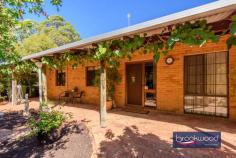 230 Naranga Pl Stoneville WA 6081 $1,100,000 Secluded at the end of a quiet Cul-de-Sac, this Hills homestead with wrap-around verandahs comes with all the extras essential to a well-rounded rural lifestyle. Sheltered outdoor living and entertaining space, a below-ground pool, a large workshop with 3-phase power, various outbuildings and gardens planted with productive fruit trees paint a picture of an idyllic Perth Hills lifestyle. 4 bedrooms 2 bathrooms 1980s-built brick and iron Country-style eat-in kitchen Formal lounge with SC fire South-facing alfresco ent Huge powered workshop B-ground swimming pool Ducted evap 6 kW solar 4.6 acres parkland cleared Top of private Cul-de-Sac A classic Australian design delivers relaxed comfort and practical style in a home with expansive outdoor living space and the extras essential to a well-rounded Hills lifestyle. An iconic wrap-around verandah leading to multiple entry points – including a formal lounge and a spacious eat-in kitchen—offers flexibility and a sense of generosity that immediately sets this property apart. The kitchen is the true heart of the home, featuring exposed brick and pine finishes and a warm, inviting atmosphere. This unmistakable sense of ‘home’ continues in the formal lounge, where a slow-combustion fireplace offers a focal point and the promise of cosy nights during the cooler months. A home office arranged off the lounge provides a secluded space for uninterrupted work and study. The principal bedroom, with a built-in robe and ensuite, sits at one end of the plan. The junior bedrooms – each with a ceiling fan and built-in robe – share the family bathroom, which is fitted with a tub, shower, and vanity. A sizeable south-facing verandah and gable-covered patio extend the living space, creating an extraordinary indoor-outdoor flow that celebrates every season. Whether basking in the soft winter sunlight or enjoying nature’s symphony on a summer night, this home offers an unparalleled living experience. Alfresco entertaining rises to new heights with pool and garden views, creating the impression of a private retreat. Arranged at one end of the patio is a spacious, lined and powered storeroom and a two-car carport. When the time for relaxing is over, this exceptional property has got you covered with a massive 9 m x 18 m 3-phase workshop with a machine shelter of the same size, an insulated sea container and various smaller outbuildings providing ample space for work, storage and creativity. The potential to keep a pony, multiple rainwater tanks, productive fruit trees – among them citrus, apple, apricot, and fig –and a 6 kW solar array add to an authentic Hills lifestyle. This secluded, family-friendly neighbourhood is only a few minutes from Mundaring, where you will find shopping, services, schools, parks, cafes and transport. The real beauty of this property is found in the tranquil natural surroundings, the freedom of abundant space and the scope to create a life in a classic Perth Hills setting.