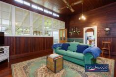 2965 Jacoby St Mundaring WA 6073 $1,000,000 In the heart of Mundaring, where the rhythm of modern life meets Western Australia’s pioneering past, stands a weatherboard and iron cottage that embodies the very essence of heritage living. Built circa 1901 by retired Bunbury harbour master Captain Thomas Scott, the remarkable “Stratheden” carries within its weatherboard walls the pioneering spirit that shaped early Western Australia. Hidden from the street by a charming picket fence and enveloped in lush, established gardens, this remarkable workers’ cottage offers a rare opportunity to inhabit a piece of living history whilst enjoying the unparalleled convenience of one of the region’s most coveted locations. 3 bedrooms 1 bathroom 1901 weatherboard & iron Striking workers’ cottage Extensive Jarrah panelling Wide jarrah floorboards High pressed metal ceilings Rear lane access to garage Estab gardens, bore retic 2023 sqm heart Mundaring Steps to Trail, park, village The extensive use of jarrah throughout this property immediately distinguishes it as a superior example of vernacular architecture, where wide floorboards and striking panelling speak to the craftsmanship and material abundance of a bygone era. Here, the integrity of the original fabric has been meticulously preserved, creating an authentic connection to the past that is increasingly rare. This is not simply a house that has been renovated; it is a heritage treasure that has been lovingly maintained, telling the story of Western Australia’s timber heritage. The approach to the home sets the tone for what lies beyond – a wide, bullnose verandah extends a gracious welcome, while pressed glass in subtle pastel hues surrounds the front door like jewels set within a frame. Living here means beginning each day with this gentle beauty, where morning light filters through coloured glass and the established gardens create a private sanctuary mere steps from Mundaring’s vibrant village centre. Upon crossing the threshold, the significance and integrity of this property become immediately apparent through the soaring ceiling, its pressed metal painted white, creating a striking vertical dimension that speaks to the generous proportions seen throughout the home. Picture rails and wide jarrah floorboards create a striking welcome that sets expectations high, and the home delivers on every promise. The entrance hall is flanked by two generously proportioned bedrooms, each graced with original windows, pressed metal ceilings and decorative fireplaces. At the end of the hallway, a pair of interior doors open to reveal the property’s masterpiece – a living room that embodies an authentic and uniquely Western Australian aesthetic. Vertical jarrah boarding rises to dado height, and horizontal panelling continues to the jarrah-clad ceiling. An expanse of eight-paned windows draws northern light into the heart of the home, creating a space where the seasons become part of daily life, where winter afternoons glow golden against the jewel-toned timber and summer mornings arrive soft and bright. Living in this room means inhabiting a space where craftsmanship and comfort converge, where every surface speaks to the skill of builders who understood both beauty and function. At one corner of this magnificent living space, a breakfast nook provides an intimate setting for morning rituals, whilst the kitchen represents a faultless melding of history and modern convenience. The original chimney breast and hearth, fitted with a Metters stove, anchor the space with authentic period detail, while pressed metal and jarrah panelling blend seamlessly with gold-flecked stone benchtops, under-bench cabinets, and contemporary appliances, including a freestanding electric oven and dishwasher. This kitchen exemplifies how heritage properties can incorporate modern elements without compromising their character. The principal bedroom, accessed via the living room, offers generous proportions. High ceilings ensure an airy, relaxed atmosphere that transforms sleep into restoration, whilst a separate walk-in robe and dressing room provide practical luxury. Reverse cycle air conditioning delivers year-round comfort, demonstrating that while heritage is honoured, contemporary expectations for comfort are uncompromised. Spanning the rear of the plan, a sunroom with a swathe of windows looking out to the rear garden creates a seamless connection between indoor and outdoor living. Terracotta floor tiles ground the space in earthy authenticity, while reverse-cycle air conditioning and direct access to both the rear garden and an alfresco entertaining zone ensure this bright space suits year-round use. A family bathroom and well-appointed laundry at either end of the sunroom complete the thoughtful arrangement of spaces. The transition to outdoor living occurs through French doors that connect the sunroom to a large, crazy-paved patio set beneath a wisteria-threaded pergola – a space where entertaining becomes effortless and where the changing seasons provide an ever-evolving backdrop. Living here means experiencing the joy of alfresco dining where privacy and tranquillity coexist with incredible accessibility to village amenities. The current owner’s dedication as a skilled and passionate gardener has created botanical magic that transforms this property from merely impressive to utterly enchanting. Bore reticulated lawns and gardens cocoon the outdoor living spaces, creating profound privacy and calm despite the home’s remarkably central location. Camellia, deciduous trees, and hardy native plants create a tapestry of colour, texture, and seasonal interest that rewards close observation and daily enjoyment. Practical considerations have not been overlooked – rear lane access leads to a powered garage and a remarkable railway carriage studio, a two-room space complete with verandah that offers endless possibilities for creative pursuits, home business ventures, or simply a peaceful retreat. A small garden shed and single carport enhance the home’s practical amenities. The location represents perhaps the property’s greatest triumph – positioned mere steps from the Sculpture Park and Heritage Trail, with the shops and services of Mundaring Village within comfortable walking distance. Schools, sporting facilities, and public transport networks are all within easy reach of this hidden oasis, creating a lifestyle where convenience never requires compromise of character or tranquillity. Living here means enjoying the best of both worlds: the peace of established gardens and heritage architecture, paired with the vibrancy and accessibility of one of the Hills’ most desirable communities. True luxury lies in authenticity, craftsmanship and connection to place. Here, in this superior example of vernacular architecture, surrounded by a mature garden landscape and positioned in Mundaring’s coveted heart, the past and present converge to create something genuinely extraordinary.