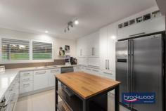 45 Strawberry Hill Dr Gidgegannup WA 6083 $1,000,000 Set amongst a landscape of gently contoured pastures and majestic gums, this two-storey Ross Squires home is a rural idyll writ large, offering a rare opportunity for fellow equestrian enthusiasts to continue a passionate legacy of horsemanship. As you arrive at the fully fenced property and approach the north-facing front door, a sense of calm descends—a feeling that only deepens as you discover the thoughtful marriage of contemporary architecture with serious equestrian infrastructure. 4 bedrooms 2 bathroom 2011-built Hardi and iron Open plan living/kitchen First-floor junior zone Barn, stable, tack, feed Round yard & arena 8 paddocks & wash bay Rainwater tanks & bore 4.94-acre pasture perfect Rural luxury horse haven Step inside, and your eyes are immediately drawn to the lush rural views framed by large windows and a sliding glass door that opens to the paved alfresco entertaining area, set under the main roof. This blissful outdoor living and entertaining space is edged with a drought-tolerant sand garden planted in a series of Corten steel beds, creating a sophisticated transition between interior comfort and the pastoral beauty beyond. Large tiles extend across much of the ground floor plan, their light, neutral tone bringing a sense of cohesion and a flexible backdrop to the embellishments of your life, whether that includes muddy riding boots or elegant dinner parties. To the right of the central living zone is a meals area and kitchen that speaks to both daily practicality and weekend entertaining. The kitchen, a modern delight, uses a limited palette of materials in predominantly soft white tones. Stone benchtops and an embarrassment of overhead and under-bench storage – including appliance nooks –surround the electric oven, four-burner gas hob and dishwasher. A corner window dressed in plantation shutters frames glimpses of surrounding paddocks, ensuring that even whilst preparing meals, the connection to the equestrian landscape remains unbroken. Judiciously positioned on the ground floor, away from the hustle and bustle of the junior bedrooms, the principal suite sits at the east end of the plan with a sliding door to the verandah, a sizeable walk-in robe and dressing room, and a fully tiled ensuite with a double shower, a central vanity with stone top and a separate WC. Split air conditioning delivers year-round comfort. A powder room and walk-through laundry with a wall of built-in storage complete the layout of the ground floor. Timber stairs ascend to the first floor, a fantastic space for children where three bedrooms open off a generous central living room with access to a south-facing balcony. Each of the junior bedrooms is carpeted and fitted with mirrored robes, with one opening to a private balcony and views towards Susannah Brook that will inspire young riders’ dreams of adventure. A treetop home office with built-in storage and a spectacular cathedral window hums with ample light and delightfully distracting views. The perfect space for homework, managing family admin, or simply watching the dancing canopy of majestic gums. The current owner, a passionate horsewoman, has developed and maintained a suite of facilities that represent a serious commitment to equine pursuits. Eight paddocks, the majority of which have electric fencing, and two with shelters, provide flexible grazing and turnout options. At the same time, powered stables with two four-metre by four-metre stalls, covered walk-out yards, a feed and tack room, and a wash-down bay with a dedicated hot water supply offer both horse and rider superior accommodation. The arena and round yard complete a setup that speaks to dedication and understanding of equestrian needs – this is infrastructure built by someone who truly knows horses. Avalon built both the stables and the drive-through barn, with the latter featuring high clearance for float storage, a bathroom/laundry with a heavy-duty machine for washing horse rugs, and a small kitchenette which opens onto a paved. A 9×6-metre garage provides secure parking and extra storage, complementing the equestrian facilities and adding to the property’s practicality. Surrounded by properties of a similar size and neighbours with an equine bent, Strawberry Hill offers a rural escape within easy reach of both Mundaring and Midland, just 30 minutes from the airport and a commutable 40 minutes from the Perth CBD. This ensures that while you enjoy the peace of country living, urban amenities remain accessible. Rainwater tanks with a filter at the house, rainwater tanks at the stable complex, and a bore with a small tank give you peace of mind in the Australian climate, as does the fire suppression system on the roof. This is a property where every detail has been considered, not just for comfortable living, but for the specific needs of those whose lives revolve around horses. It understands that the view from the kitchen window is made infinitely more beautiful by horses grazing in the morning light.