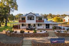 45 Strawberry Hill Dr Gidgegannup WA 6083 $1,000,000 Set amongst a landscape of gently contoured pastures and majestic gums, this two-storey Ross Squires home is a rural idyll writ large, offering a rare opportunity for fellow equestrian enthusiasts to continue a passionate legacy of horsemanship. As you arrive at the fully fenced property and approach the north-facing front door, a sense of calm descends—a feeling that only deepens as you discover the thoughtful marriage of contemporary architecture with serious equestrian infrastructure. 4 bedrooms 2 bathroom 2011-built Hardi and iron Open plan living/kitchen First-floor junior zone Barn, stable, tack, feed Round yard & arena 8 paddocks & wash bay Rainwater tanks & bore 4.94-acre pasture perfect Rural luxury horse haven Step inside, and your eyes are immediately drawn to the lush rural views framed by large windows and a sliding glass door that opens to the paved alfresco entertaining area, set under the main roof. This blissful outdoor living and entertaining space is edged with a drought-tolerant sand garden planted in a series of Corten steel beds, creating a sophisticated transition between interior comfort and the pastoral beauty beyond. Large tiles extend across much of the ground floor plan, their light, neutral tone bringing a sense of cohesion and a flexible backdrop to the embellishments of your life, whether that includes muddy riding boots or elegant dinner parties. To the right of the central living zone is a meals area and kitchen that speaks to both daily practicality and weekend entertaining. The kitchen, a modern delight, uses a limited palette of materials in predominantly soft white tones. Stone benchtops and an embarrassment of overhead and under-bench storage – including appliance nooks –surround the electric oven, four-burner gas hob and dishwasher. A corner window dressed in plantation shutters frames glimpses of surrounding paddocks, ensuring that even whilst preparing meals, the connection to the equestrian landscape remains unbroken. Judiciously positioned on the ground floor, away from the hustle and bustle of the junior bedrooms, the principal suite sits at the east end of the plan with a sliding door to the verandah, a sizeable walk-in robe and dressing room, and a fully tiled ensuite with a double shower, a central vanity with stone top and a separate WC. Split air conditioning delivers year-round comfort. A powder room and walk-through laundry with a wall of built-in storage complete the layout of the ground floor. Timber stairs ascend to the first floor, a fantastic space for children where three bedrooms open off a generous central living room with access to a south-facing balcony. Each of the junior bedrooms is carpeted and fitted with mirrored robes, with one opening to a private balcony and views towards Susannah Brook that will inspire young riders’ dreams of adventure. A treetop home office with built-in storage and a spectacular cathedral window hums with ample light and delightfully distracting views. The perfect space for homework, managing family admin, or simply watching the dancing canopy of majestic gums. The current owner, a passionate horsewoman, has developed and maintained a suite of facilities that represent a serious commitment to equine pursuits. Eight paddocks, the majority of which have electric fencing, and two with shelters, provide flexible grazing and turnout options. At the same time, powered stables with two four-metre by four-metre stalls, covered walk-out yards, a feed and tack room, and a wash-down bay with a dedicated hot water supply offer both horse and rider superior accommodation. The arena and round yard complete a setup that speaks to dedication and understanding of equestrian needs – this is infrastructure built by someone who truly knows horses. Avalon built both the stables and the drive-through barn, with the latter featuring high clearance for float storage, a bathroom/laundry with a heavy-duty machine for washing horse rugs, and a small kitchenette which opens onto a paved. A 9×6-metre garage provides secure parking and extra storage, complementing the equestrian facilities and adding to the property’s practicality. Surrounded by properties of a similar size and neighbours with an equine bent, Strawberry Hill offers a rural escape within easy reach of both Mundaring and Midland, just 30 minutes from the airport and a commutable 40 minutes from the Perth CBD. This ensures that while you enjoy the peace of country living, urban amenities remain accessible. Rainwater tanks with a filter at the house, rainwater tanks at the stable complex, and a bore with a small tank give you peace of mind in the Australian climate, as does the fire suppression system on the roof. This is a property where every detail has been considered, not just for comfortable living, but for the specific needs of those whose lives revolve around horses. It understands that the view from the kitchen window is made infinitely more beautiful by horses grazing in the morning light.