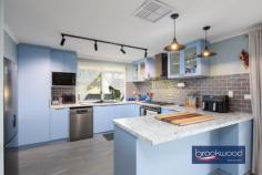 33 Tamarillo Ct Bakers Hill WA 6562 $949,000 An as-new Colorbond steel framed home set on 3.26 acres of park-like acreage planted with deciduous trees for shade, natives for wildlife habitat and jacarandas for summer colour. This property delivers genuine space – inside and out – with a three-bedroom primary residence, separate one-bedroom accommodation, two paddocks and the kind of big sky that reminds you what evening light actually looks like. Reclaimed materials meet contemporary country style throughout, from Art Deco leadlight windows to repurposed farm machinery that lends structure to the garden. 3 bedrooms, 2 bathrooms Colorbond Queenslander home Open-plan kitchen/family/meals Fantastic activity/games room Generous interior spaces Wrap-around verandah Sep 1 × 1 accommodation 2 paddocks, sheds, chooks 3.26 level acres fenced 3-meter-wide verandahs The main residence sits proudly elevated, with reclaimed Art Deco leadlight windows screening the corners of the wraparound verandah. Entry is via a wide staircase framed by multicoloured recycled paving. The thoughtful reuse continues—an old bedhead repurposed as a balustrade, and disused farm machinery cleverly lending structure to garden beds. An inspired material palette and a clear eye for making things work give this home genuine personality. The open-plan kitchen, family, and meals area feels genuinely spacious. A 900 mm freestanding self-cleaning oven anchors the kitchen, finished in soft blue cabinetry with marble-look benchtops and a grey subway-tile splashback. Hybrid flooring runs across the entire plan, connecting kitchen to meals to family room in a continuous flow that makes the space feel larger than its footprint and handles the inevitable traffic of daily life without complaint. The meals area opens directly to the southern verandah – breakfast outside becomes routine, not an occasion. A large casement opening and double-sided Jarrahdale slow-combustion fire, with a pressed-metal surround, link the central living area to the adjoining activity room. Timber floors and generous proportions make this a great, open space where a pool table fits comfortably, creating a laid-back spot for family fun, entertaining and unwinding together. The principal suite claims the front corner of the plan, a bay window framing views across the acreage. The room is generous – king-size bed, space for a reading chair, split-system air conditioning, and direct deck access. The ensuite features a relaxing spa bath, a detail that transforms a standard evening into a genuine wind-down. Two junior bedrooms share the family bathroom – one a double, the other a large king with reverse-cycle air conditioning and its own deck access. The family bathroom includes both a shower and a tub, with a separate WC accessed via the walk-through laundry. The laundry itself uses a moody palette, continuing the contemporary country aesthetic that runs throughout. The separate accommodation elevates this property. A large verandah with outdoor blinds leads to a multi-use room with a pitched roof, slow-combustion fire, evaporative cooling, and a kitchen corner. This space could serve as additional accommodation for visiting family, a teenager’s retreat that offers everyone breathing room, or a home-based business office /showroom. A sheltered outdoor fire pit extends the usable space – somewhere to gather on clear nights when the stars do all the talking. The large bathroom/laundry and partially enclosed rear room (ideal as bedroom or office) add genuine flexibility. Outside, the 3.26 acres delivers fenced paddocks – one with shelter – provide scope for a pony, alpacas, or simply the peace that comes with room to breathe and move. The chicken coop is in place. A woodshed, garden shed, carport, and an old bus converted to a storage room. The property runs a 5-kW solar array and connects to scheme water, supplemented by a small rainwater tank. The acreage itself has been planted with trees for shade and jacarandas that announce summer in violet. The garden incorporates recycled elements throughout – a creative approach that gives the property character. Bakers Hill township sits five minutes away – enough distance to feel separate, close enough that milk runs don’t become expeditions. Northam is 20 minutes, Mundaring 25 minutes, Perth Airport approximately 50 minutes. This is the Wheatbelt fringe – close enough to Perth for work commutes, far enough out that the night sky actually matters. The property suits anyone seeking space without isolation, contemporary comfort without suburban compression and the particular satisfaction of hearing birdsong rather than traffic as the day begins.