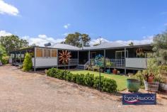 33 Tamarillo Ct Bakers Hill WA 6562 $949,000 An as-new Colorbond steel framed home set on 3.26 acres of park-like acreage planted with deciduous trees for shade, natives for wildlife habitat and jacarandas for summer colour. This property delivers genuine space – inside and out – with a three-bedroom primary residence, separate one-bedroom accommodation, two paddocks and the kind of big sky that reminds you what evening light actually looks like. Reclaimed materials meet contemporary country style throughout, from Art Deco leadlight windows to repurposed farm machinery that lends structure to the garden. 3 bedrooms, 2 bathrooms Colorbond Queenslander home Open-plan kitchen/family/meals Fantastic activity/games room Generous interior spaces Wrap-around verandah Sep 1 × 1 accommodation 2 paddocks, sheds, chooks 3.26 level acres fenced 3-meter-wide verandahs The main residence sits proudly elevated, with reclaimed Art Deco leadlight windows screening the corners of the wraparound verandah. Entry is via a wide staircase framed by multicoloured recycled paving. The thoughtful reuse continues—an old bedhead repurposed as a balustrade, and disused farm machinery cleverly lending structure to garden beds. An inspired material palette and a clear eye for making things work give this home genuine personality. The open-plan kitchen, family, and meals area feels genuinely spacious. A 900 mm freestanding self-cleaning oven anchors the kitchen, finished in soft blue cabinetry with marble-look benchtops and a grey subway-tile splashback. Hybrid flooring runs across the entire plan, connecting kitchen to meals to family room in a continuous flow that makes the space feel larger than its footprint and handles the inevitable traffic of daily life without complaint. The meals area opens directly to the southern verandah – breakfast outside becomes routine, not an occasion. A large casement opening and double-sided Jarrahdale slow-combustion fire, with a pressed-metal surround, link the central living area to the adjoining activity room. Timber floors and generous proportions make this a great, open space where a pool table fits comfortably, creating a laid-back spot for family fun, entertaining and unwinding together. The principal suite claims the front corner of the plan, a bay window framing views across the acreage. The room is generous – king-size bed, space for a reading chair, split-system air conditioning, and direct deck access. The ensuite features a relaxing spa bath, a detail that transforms a standard evening into a genuine wind-down. Two junior bedrooms share the family bathroom – one a double, the other a large king with reverse-cycle air conditioning and its own deck access. The family bathroom includes both a shower and a tub, with a separate WC accessed via the walk-through laundry. The laundry itself uses a moody palette, continuing the contemporary country aesthetic that runs throughout. The separate accommodation elevates this property. A large verandah with outdoor blinds leads to a multi-use room with a pitched roof, slow-combustion fire, evaporative cooling, and a kitchen corner. This space could serve as additional accommodation for visiting family, a teenager’s retreat that offers everyone breathing room, or a home-based business office /showroom. A sheltered outdoor fire pit extends the usable space – somewhere to gather on clear nights when the stars do all the talking. The large bathroom/laundry and partially enclosed rear room (ideal as bedroom or office) add genuine flexibility. Outside, the 3.26 acres delivers fenced paddocks – one with shelter – provide scope for a pony, alpacas, or simply the peace that comes with room to breathe and move. The chicken coop is in place. A woodshed, garden shed, carport, and an old bus converted to a storage room. The property runs a 5-kW solar array and connects to scheme water, supplemented by a small rainwater tank. The acreage itself has been planted with trees for shade and jacarandas that announce summer in violet. The garden incorporates recycled elements throughout – a creative approach that gives the property character. Bakers Hill township sits five minutes away – enough distance to feel separate, close enough that milk runs don’t become expeditions. Northam is 20 minutes, Mundaring 25 minutes, Perth Airport approximately 50 minutes. This is the Wheatbelt fringe – close enough to Perth for work commutes, far enough out that the night sky actually matters. The property suits anyone seeking space without isolation, contemporary comfort without suburban compression and the particular satisfaction of hearing birdsong rather than traffic as the day begins.